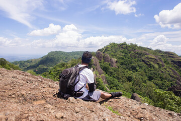 Man hiker with a backpack on top of the mountain back
