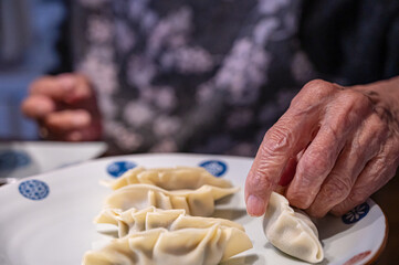 餃子作りをするご年配女性の手