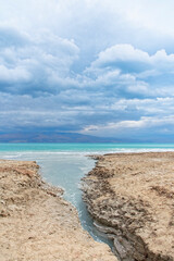 Fototapeta na wymiar Sinkhole filled with turquoise water, near Dead Sea coastline. Hole formed when underground salt is dissolved by freshwater intrusion, due to continuing sea-level drop. . High quality photo