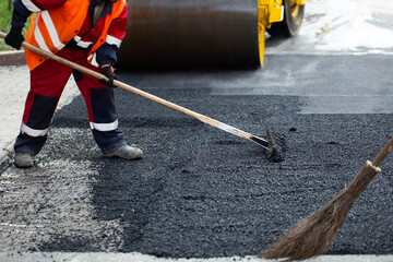 The road workers' working group updates part of the road with fresh hot asphalt and smoothes it for...