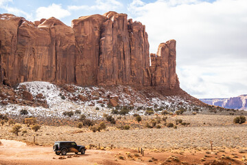 A black Jeep Wrangler alone in a southwest desert landscape will large cliffs in the distance in...