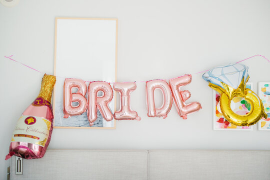 Cute bachelorette party bunting as pink glitter letters and engagement ring Bridal shower party with friends Pink bride balloons in background