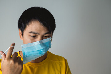 The man twists medical mask’s straps. This method helps to improve the fit and filtration of mask. Protection global pandemic of coronavirus. Other name of this disease calls COVID-19.