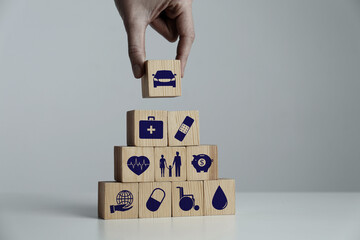 Woman building pyramid of wooden cubes with different icons at white table indoors, closeup....
