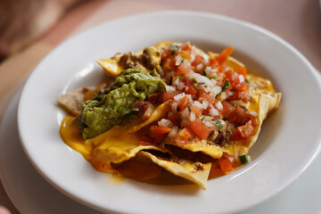 Un plato de nachos con queso, carne y guacamole