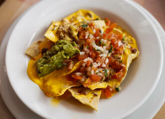 Un plato de nachos con queso, carne y guacamole