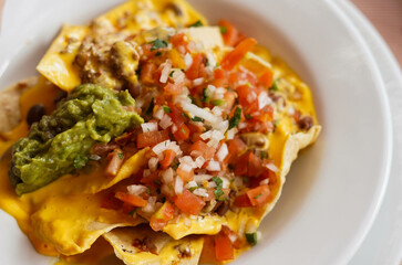 Un plato de nachos con queso, carne y guacamole