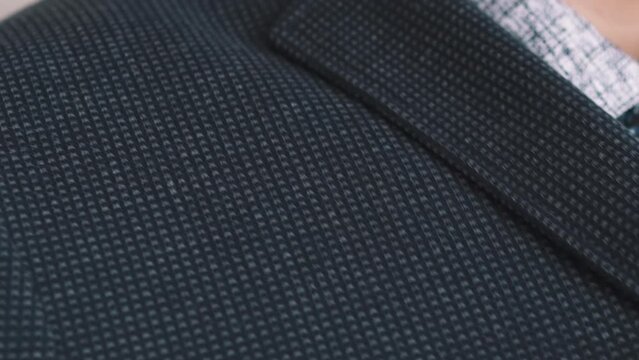 Man in patterned shirt puts on dark jacket extreme close view slow motion. Businessman wearing office suit in workplace. Formal clothes dresscode