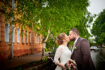 A wedding couple in town on a summer day. Bride and groom in white dress walking on the street