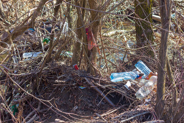 Garbage plastic bottles and plastic bags on the river bank, nature pollution, environmental disaster, selective focus	