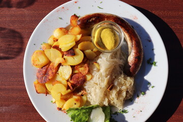 Deutsches Gericht: Bratwurst mit Bratkartoffeln und Sauerkraut.