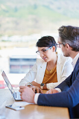 Sharing ideas for the betterment of business. Shot of two colleagues working on a laptop at a desk...
