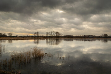 Fototapeta premium Dark clouds over the frozen lake, winter view