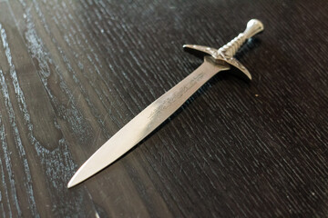 Silver Sword with Scroll Work on Dark Wood Table