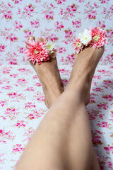 Obraz na płótnie Canvas Woman legs and flowers against colored background