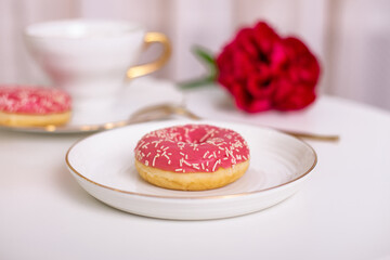 
Cup of tea, sweet strawberry donut on golden plate with hydrangea flower

