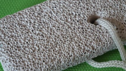 A block of pumice stone on a green surface, close-up.
