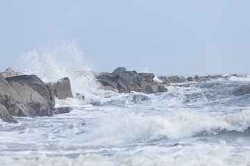 Rocks on the beach, water splashing, ocean, waves, blue sky