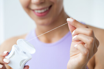 Portrait of beautiful woman cleaning teeth with dental floss