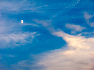 Half moon in a blue cloudy sky