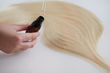 Curl female hair, balm or hair mask isolated on white background . Close-up oil bottle and recovery hair. Concept hairdresser spa salon. hair restoration and treatment after winter
