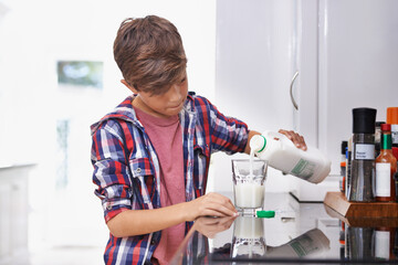 Healthy choices from a young age. A young boy pouring himself a glass of milk in the kitchen.