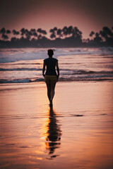 Fototapeta premium woman silhouette walking on sunset beach