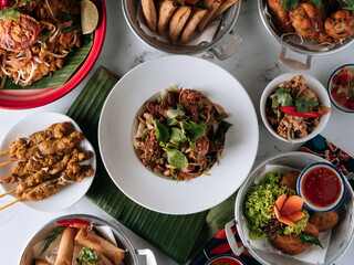 selective choice food table Shell Crab noodle , Chicken Satay, Spring Roll, Curry Samosa, fish cake, Folks Drumlet, Pork Jar Salad in a dish isolated on mat top view on grey marble background
