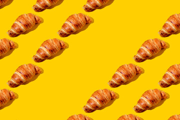 Pattern made of Fresh Croissant on a yellow background. Flat lay style.