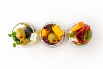 Serving appetizers in a tasting glass: salmon, prawn, cheese, ham, caviar and olives. Beautifully decorated catering banquet menu. Food snacks and appetizers for buffet. Isolated on white backgroun