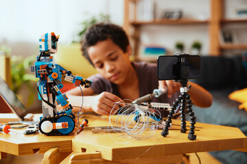An educated little boy recording himself for a vlog and making a robot. Education in electronics and artificial intelligence. - 490769930