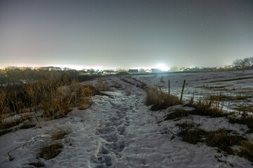 landscape with snow forest in the night . Night landscape. Nightsky and clouds . Stars in the sky . Lights of the city . 