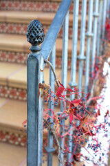 Street stairs decorated with ceramic tiles with iron forged handrails entwined with a plant with...