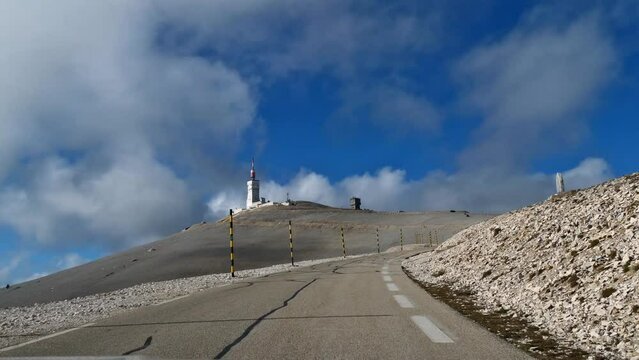 POV of car approaching the peak of mountain Mont Ventoux in Provence, southern France, on windy day in autumn season on curvy road between limestone rocks.