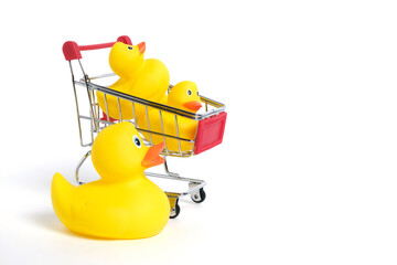 Yellow rubber ducks in shopping cart on a white background.Children goods and purchases. © freeman83