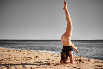 A closeup of a young woman doing a yoga on the beach