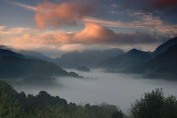 Colorful sky over sea of fog in a valley in a morning