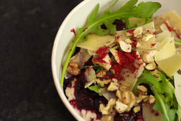 Vegan food. Breakfast oatmeal porridge with cherries, parmesan, arugula and nuts on a dark background in an eco paper box. Healthy balanced food. Top view, overhead, banner