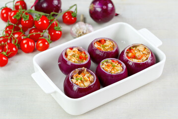 Stuffed onions recipe. Red onions stuffed with meat and vegetables in white bowl ready to bake in the oven. close up