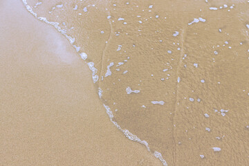 Minimalist photography with the line of a wave gently breaking on the sand