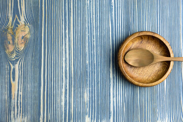 Empty plate and spoon on a wooden table.