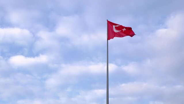 Turkish flag waving in blue sky with clouds , Republic Square in Antalya. A lively town square with equestrian statue of former President Ataturk surrounded by numerous cafes.