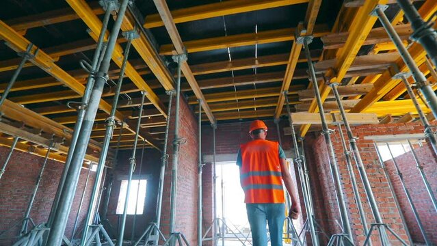 The builder goes inside the building under construction. Builder inside the house. The builder goes to the construction site.