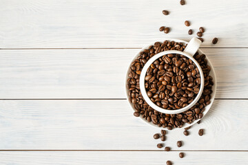a cup with coffee beans on a light wooden background with a copy space