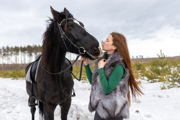 A woman and a black horse on a walk. Favorite pet. Horse riding in winter