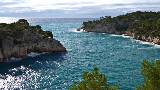 Beautiful view of the rough mediterranean sea at bay Calanque de Port-Miou near Cassis at the French Riviera in southern France in autumn season with characteristic rocks covered by green pine trees.