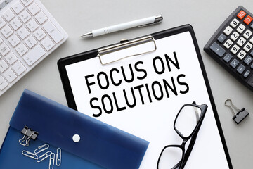 Focus on solutions - Folder, clipboard text on white clean paper, blue folder and glasses, top...