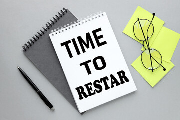 Time to Restart top view of an open notepad with text and yellow stickers. magnifier. glasses