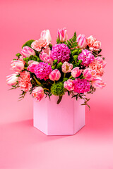 Bouquet of flowers in cardboard box on a pink background