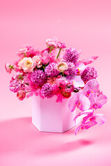 Bouquet of flowers in cardboard box on a pink background